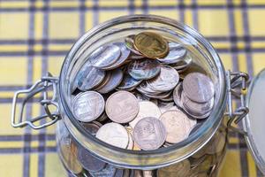 Many coins in glass jar, saving. photo