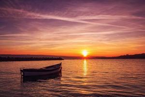 Beautiful light composition and mood of the boat in calm water at sunset photo