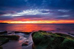 Sea sunrise with rocks with moss on the beach photo