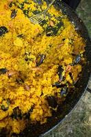 paella comida tradicional española. paella preparada en una sartén grande en la calle en llamas foto