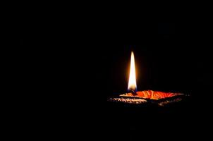 Selective focus on flame of clay diya lamp lit on dark background. Diwali festival concept. photo