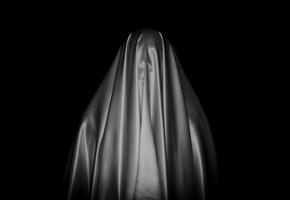 Scary white ghost sheet on black background for Halloween Festival concept. photo