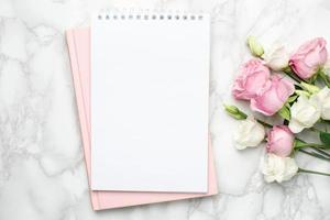Beautiful white and pink roses flower and notebook on marble background photo