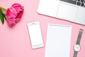 Mobile phone mock up, notebook and peony flower on pink pastel table in flat lay style. Woman working desk. photo