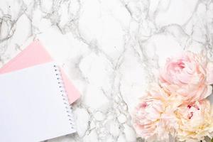 Marble background with white peony flower and notebook. Women business day photo