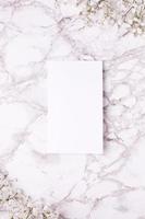 Empty card with white flowers on marble table top view and flat lay style. photo