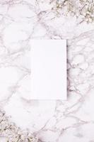 Empty card with white flowers on marble table top view and flat lay style. photo