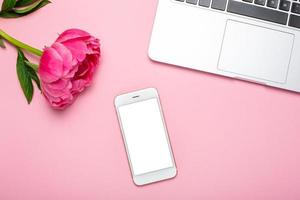 Mobile phone mock up and peony flower on pink pastel table in flat lay style. Woman working desk. photo