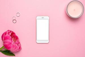 Mobile phone mock up and peony flower on pink pastel table in flat lay style. Woman working desk.Summer colour photo