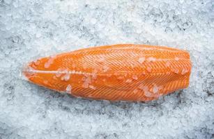 Fresh raw salmon fish steak on ice over gray stone background. photo