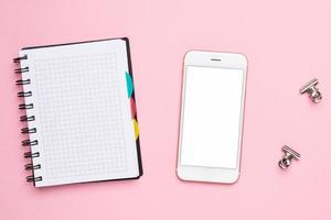 Mobile phone and notebook in a cage on a pink background photo