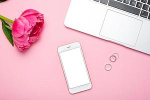 Mobile phone mock up and peony flower on pink pastel table in flat lay style. Woman working desk.Summer colour photo