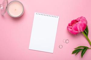 Beautiful pink peony flower and notebook with copy space for your text on pastel pink background photo