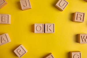 The word ok is made up of square wooden cubes with letters on a yellow background photo