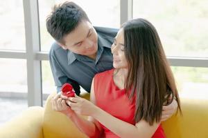 mujer joven feliz que recibe el anillo de compromiso de su novio foto