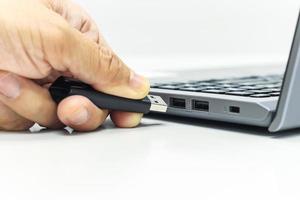 la mano del hombre de negocios empuja la unidad usb al puerto usb para transferir datos de la computadora portátil o guardar datos foto