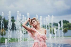 chica elegante caminando y posando vestida en la ciudad cerca de fuentes foto