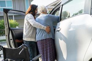 Caregiver help Asian senior or elderly old lady woman patient get to her car, healthy strong medical concept. photo
