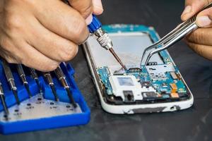 Technician repairing inside of mobile phone by soldering iron. Integrated Circuit. the concept of data, hardware, technology. photo