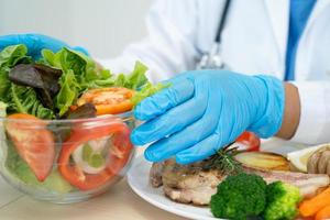 Nutritionist doctor holding various healthy fresh vegetables for patient. photo