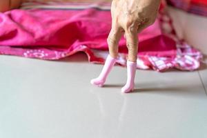 The old woman's hand plays pink plastic boots toy and post it like a model's post. photo