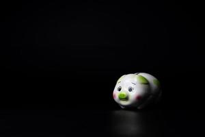 Isolated sad piggy bank on the black background with copy space. photo