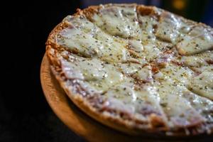 La pizza de jamón con queso se rellena con orégano en la mano de una mujer. Evento de pista de comida en bangkok, thialand. foto