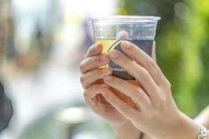 plastic cup in female hand with blur background. photo