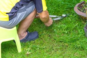 Asian man sat on plastic chair and cut the grass in his garden in the front of home. photo