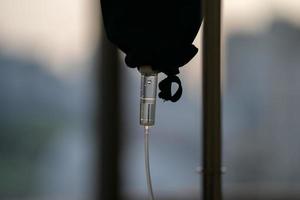 close up to the medical tool, saline drip in the dark silhouette theme on the evening window light. photo