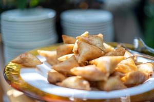 A samosa is a fried or baked pastry with a savoury filling, such as spiced potatoes, onions, peas, meat, or lentils. It may take different forms, including triangular, cone, or half-moon shapes. photo