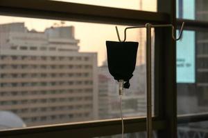 close up to the medical tool, saline drip in the dark silhouette theme on the evening window light. photo