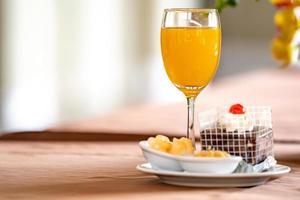 Orange juice in champagne glass with cake and bagery beside. photo