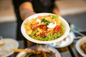 Somtum Spicy papaya salad with boiled corn in paper dish at foodtruck street food event., Bangkok, Thailand. photo