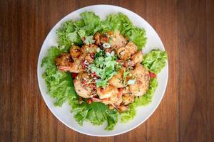 Fried Seafood shrimp prawn fish mussel squid fish on the salad vegetagle in white circle dish on wood table. photo