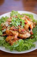 Fried Seafood shrimp prawn fish mussel squid fish on the salad vegetagle in white circle dish on wood table. photo