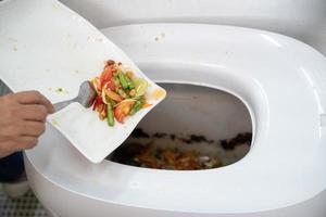 Asian woman seperated food in her white dish to composted hitech machine to feed microorganism inside for create good fertilizer to plantation. photo