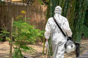 especialista profesional caminando y observando alrededor del jardín al aire libre para preparar una solución líquida desinfectante para rociar para matar el coronavirus covid 19. foto