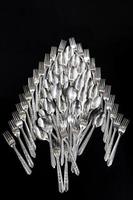 topview of Spoons and forks are arranged on the black cloth background. photo