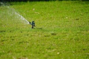 sistema de trabajo de césped por aspersión, trabajando en el campo en el jardín. foto