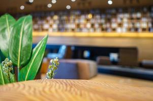 Wood table with blur library background decorated by big green leaf and white little flower for any product shot photo