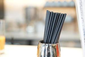 Black paper straw in the stainless cup at the restaurant bar. It's the choice for reduce the plastic waste because It's biodegradable waste to save the animal and world from plastic waste. photo