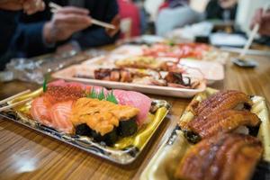 Shaddy sushi, and others sush salmon, otoro, eel, grilled shrimp, crab are arranged on the table ready to eat. photo