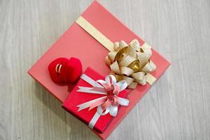 caja de regalo con cinta roja y anillo de oro en la mesa de madera foto