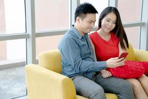 pareja sonriente mirando un teléfono inteligente foto