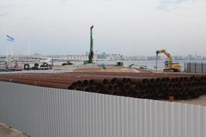 An excavator makes a mound of sand on the seashore. Protection of the beach area for the winter from flooding. Industrial construction equipment and machinery. photo