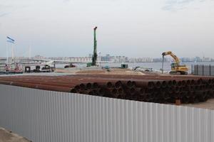 una excavadora hace un montículo de arena en la orilla del mar. protección de la zona de la playa para el invierno contra inundaciones. equipos y maquinaria de construcción industrial. foto