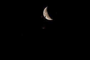 hermoso cuarto de luna sobre el casco antiguo de riga detrás de las cúpulas del reloj de la catedral. foto