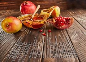 Rosh hashanah - jewish new year holiday concept. Bowl with honey, apples, pomegranates, shofar on a wooden vintage background. lettering happy rosh hashanah photo