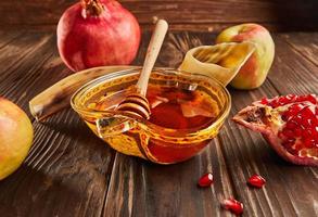 Rosh hashanah - jewish new year holiday concept. Bowl in the shape of an apple with honey, apples, pomegranates, shofar on wooden vintage background photo